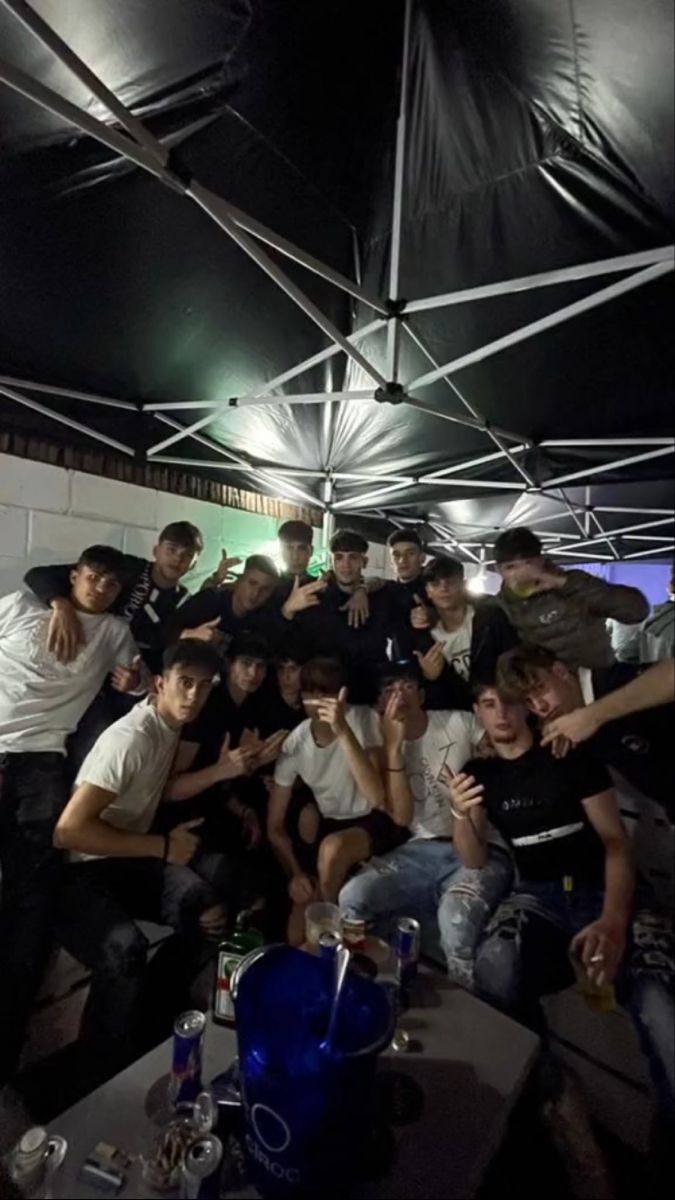 a group of young men posing for a photo under an umbrella in a dark room