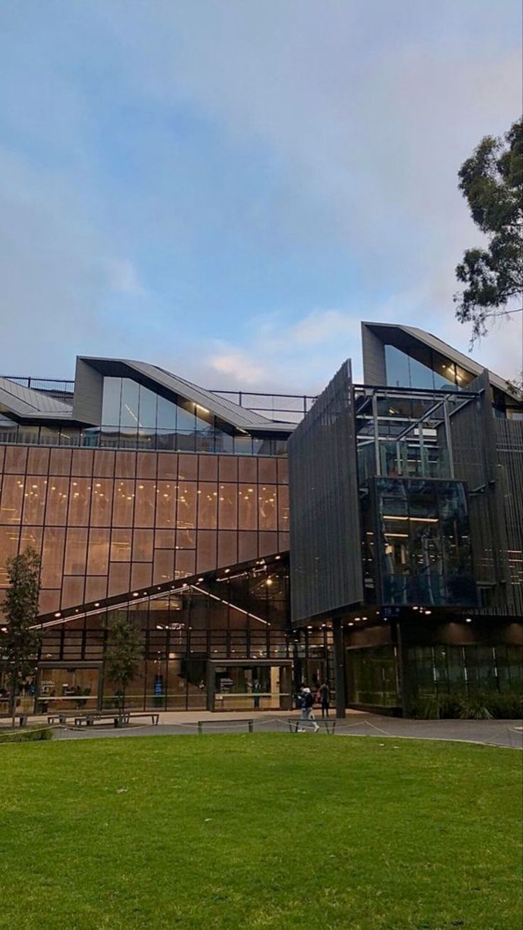 a large building with many windows on the side of it and grass in front of it