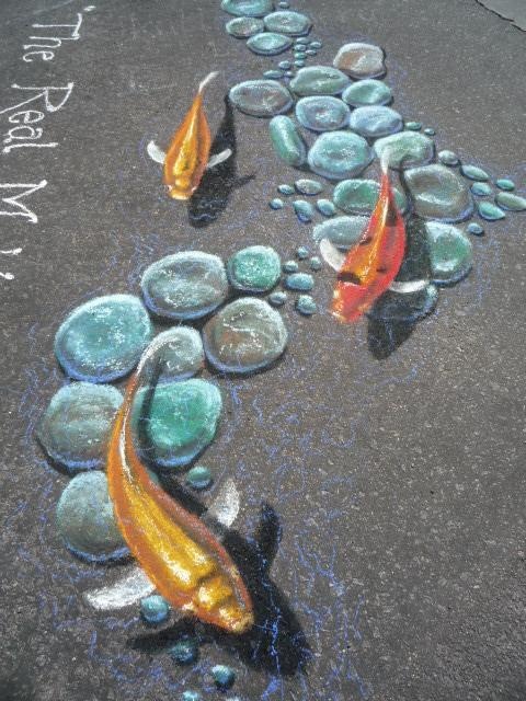 two orange and black koi fish swimming in the water next to some rocks on the ground