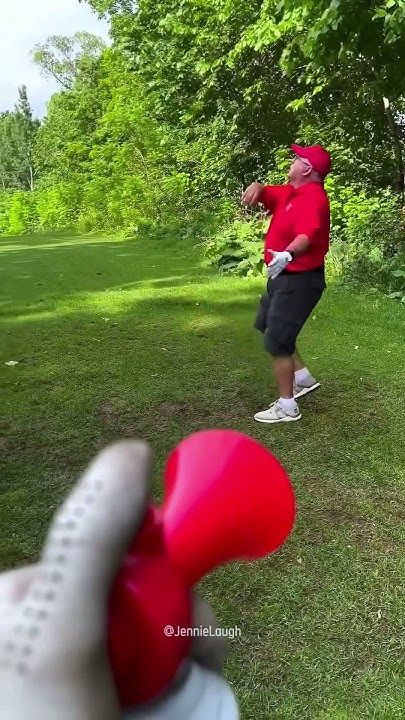 a man is throwing a red frisbee in the park while another person watches