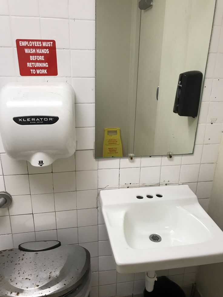 a bathroom with a sink, mirror and trash can