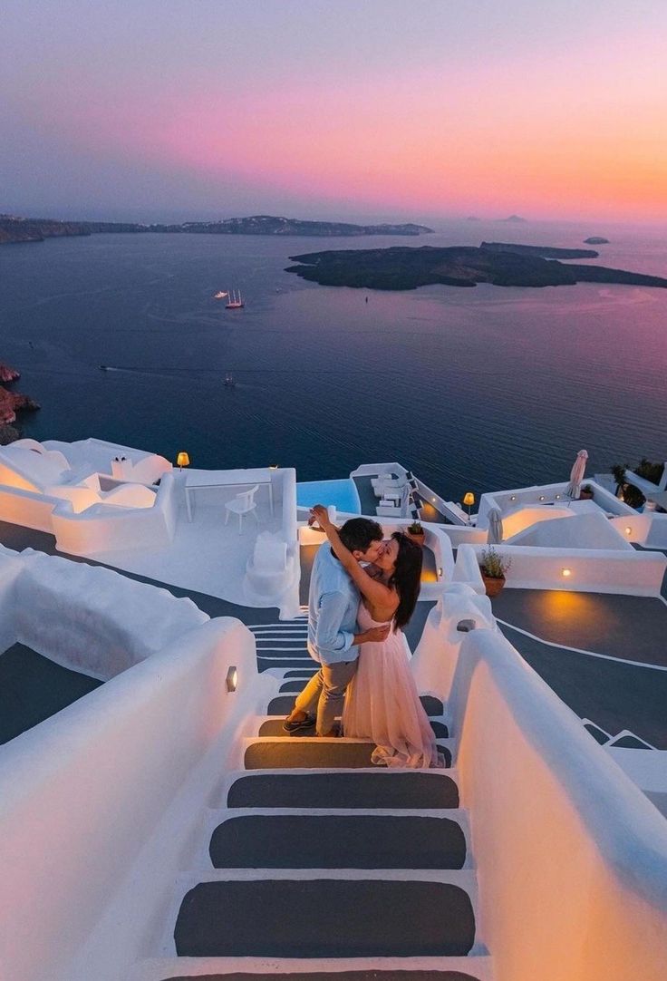 the bride and groom are walking down the stairs to their destination at sunset in oia