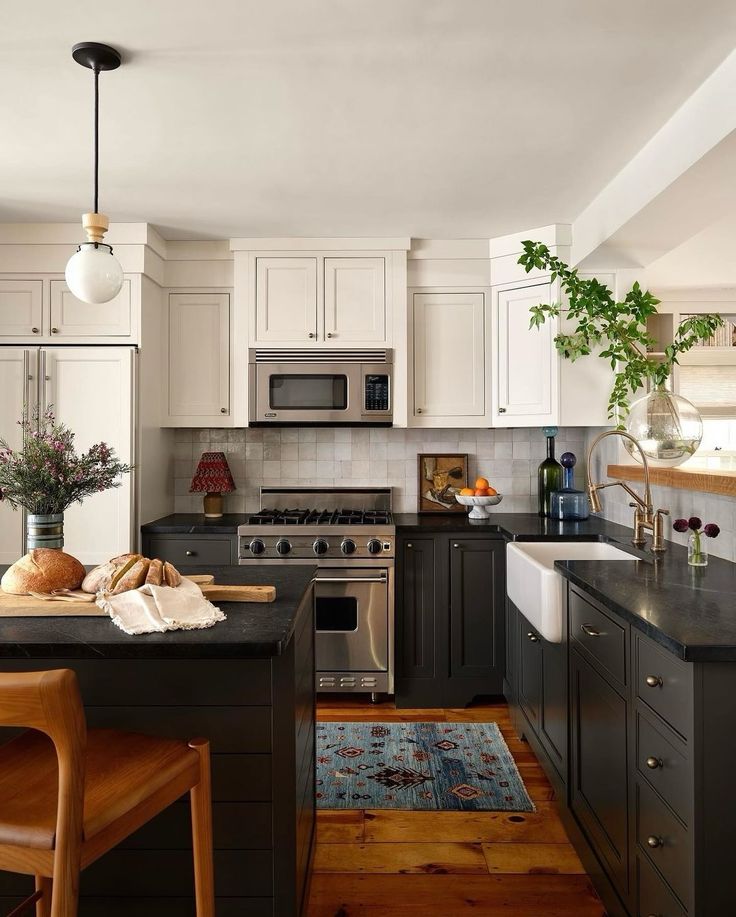 a kitchen with white cabinets, black counter tops and an island in front of the stove