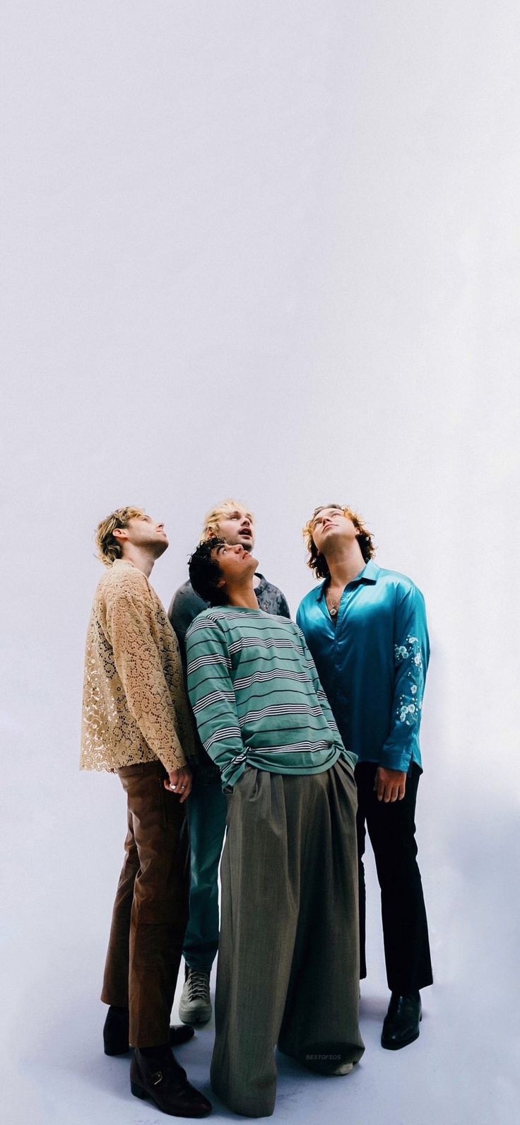 three people standing next to each other in front of a white wall and looking up at the sky