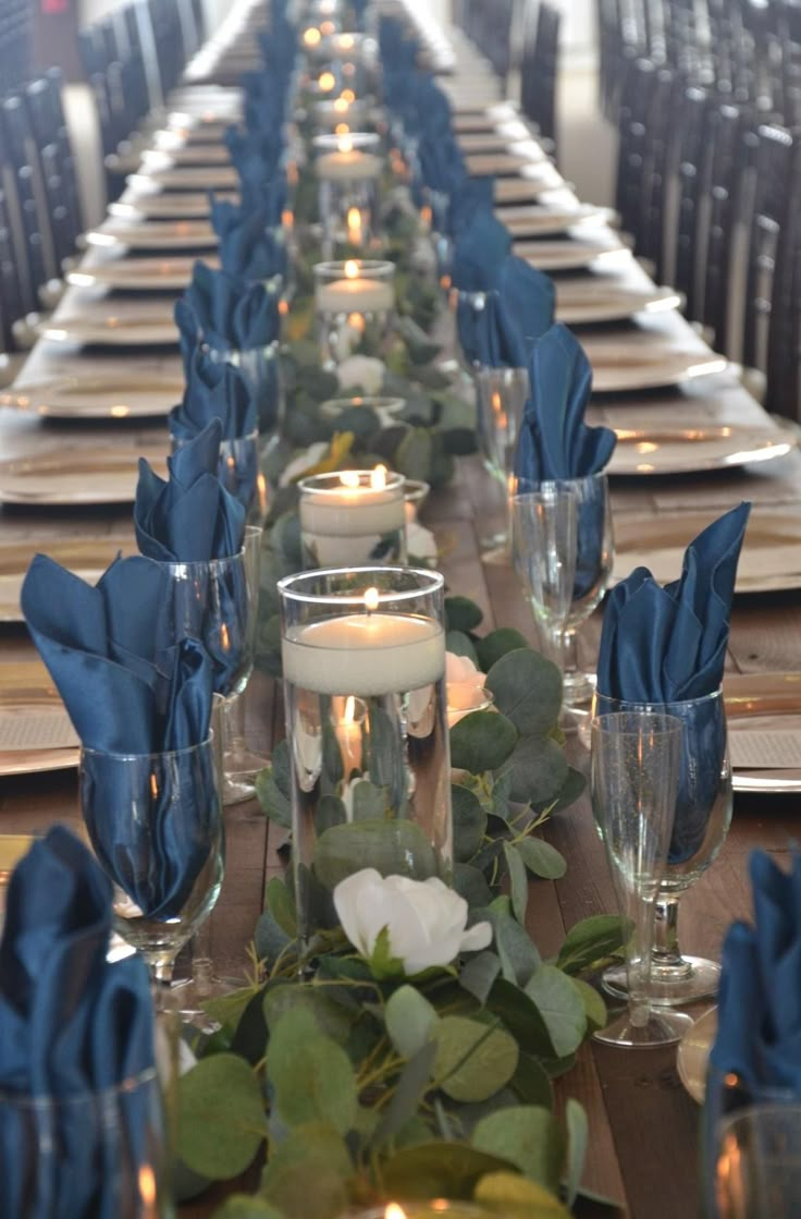 a long table is set with candles and blue napkins