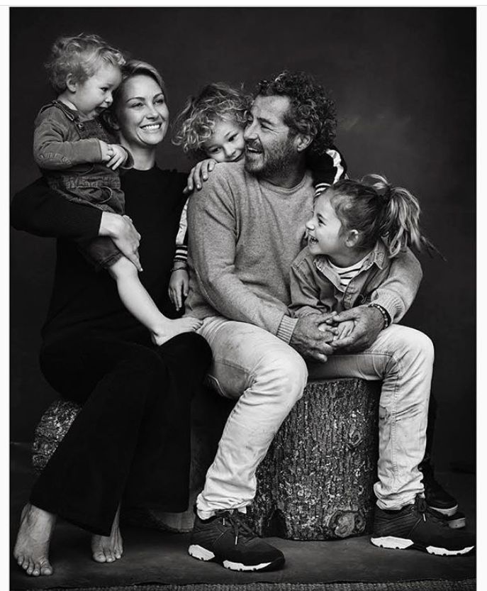 a black and white photo of a family sitting on a tree stump with their arms around each other