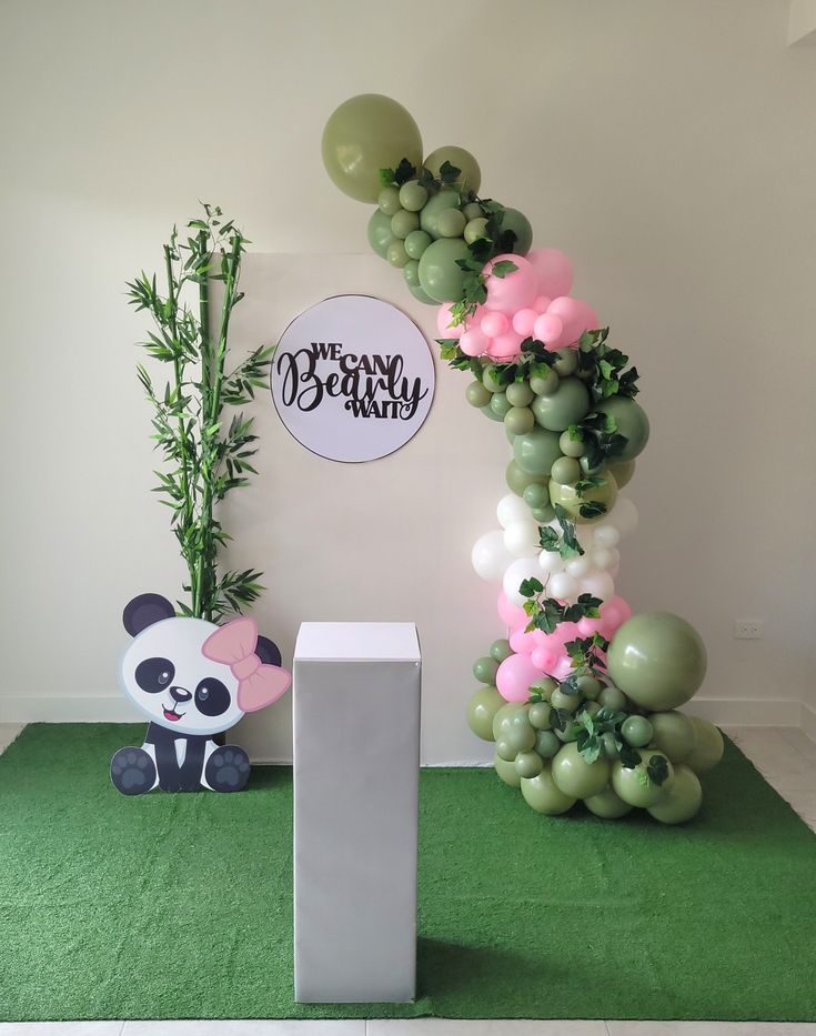 a panda balloon arch with balloons and greenery on the floor in front of it