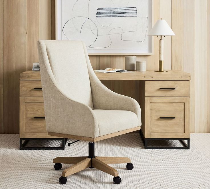 an office chair sits in front of a desk with drawers and a painting on the wall