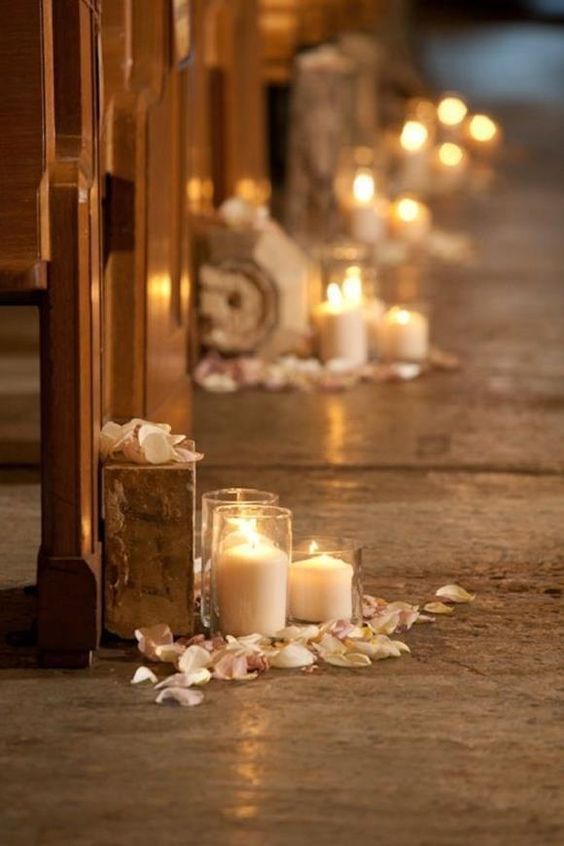 candles are lined up on the floor in front of pews