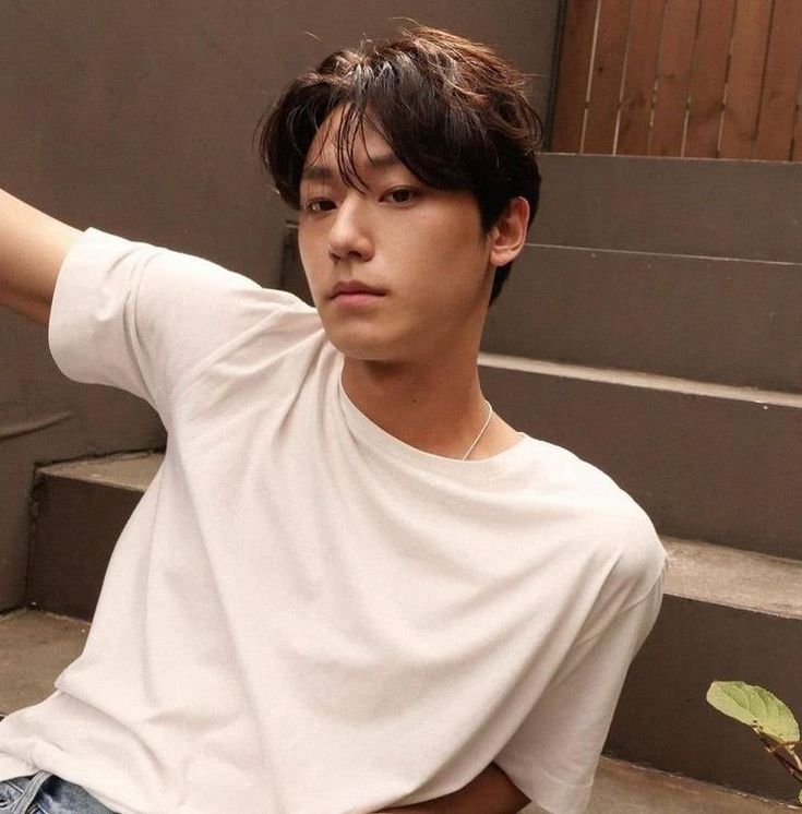 a young man sitting on the steps with his hand in his pocket