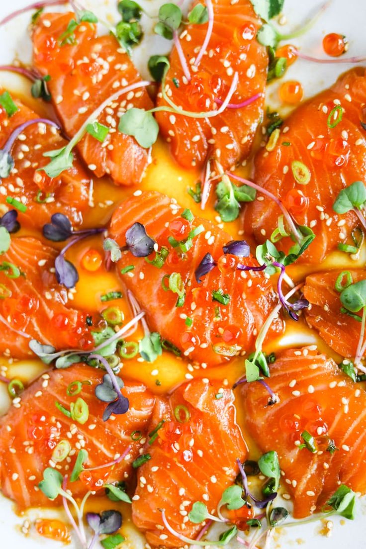 a white plate topped with salmon covered in sesame seeds and garnished with green onions