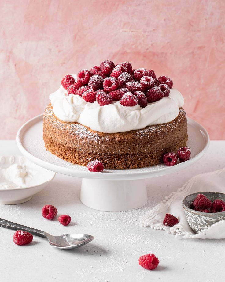 a cake topped with whipped cream and raspberries on top of a white plate