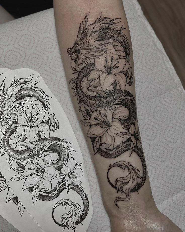 a dragon and flower tattoo on the left leg, next to a paper with an ink pen