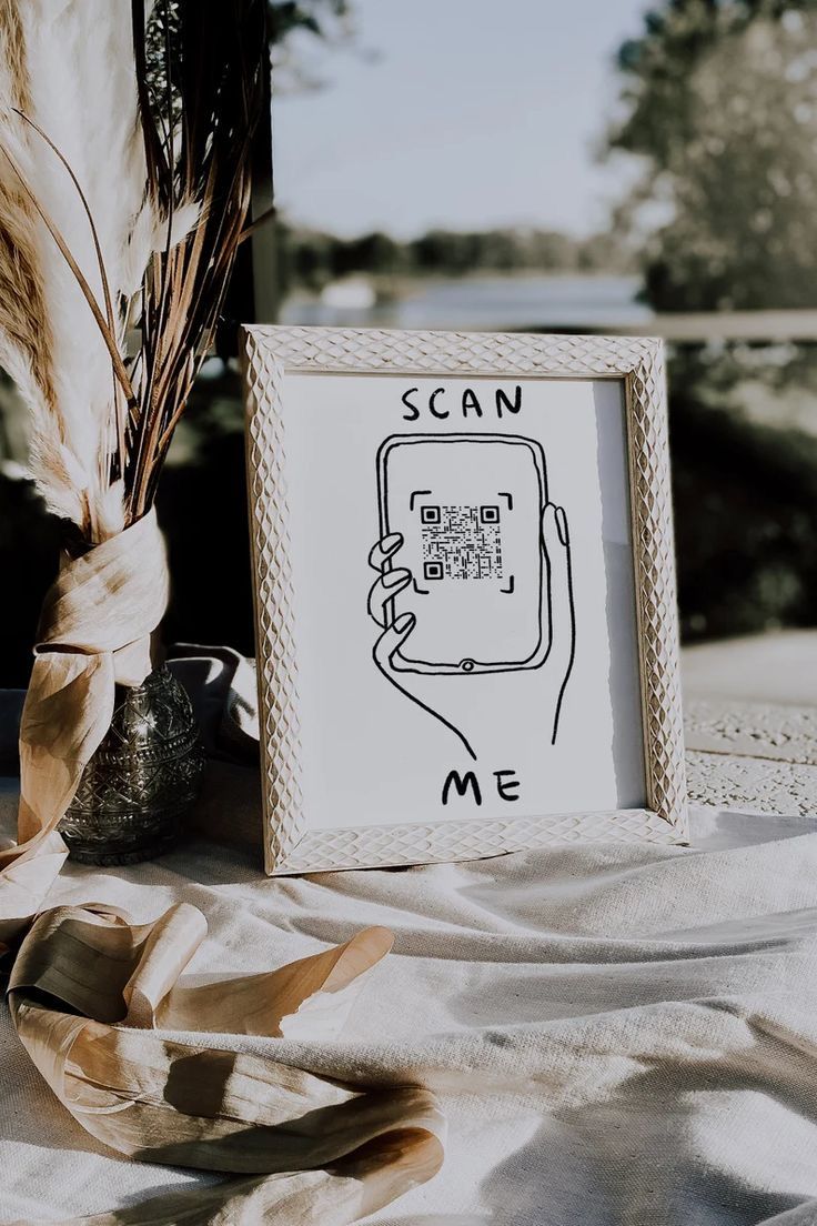 a photo frame sitting on top of a table next to a vase and dried plant