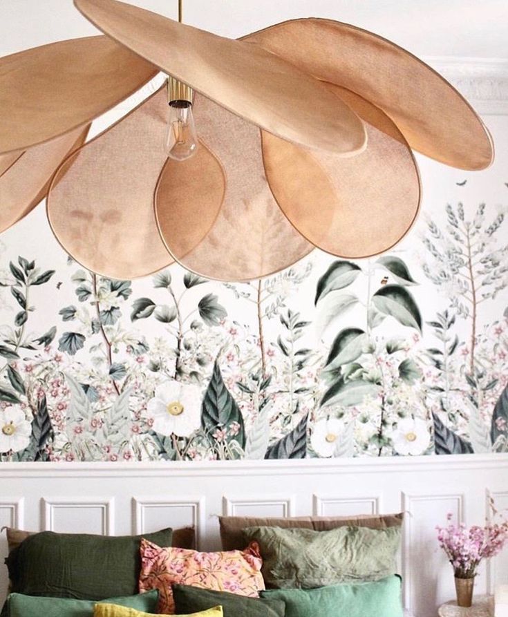 a living room filled with lots of furniture and flowers on the wall behind it is a large wooden chandelier