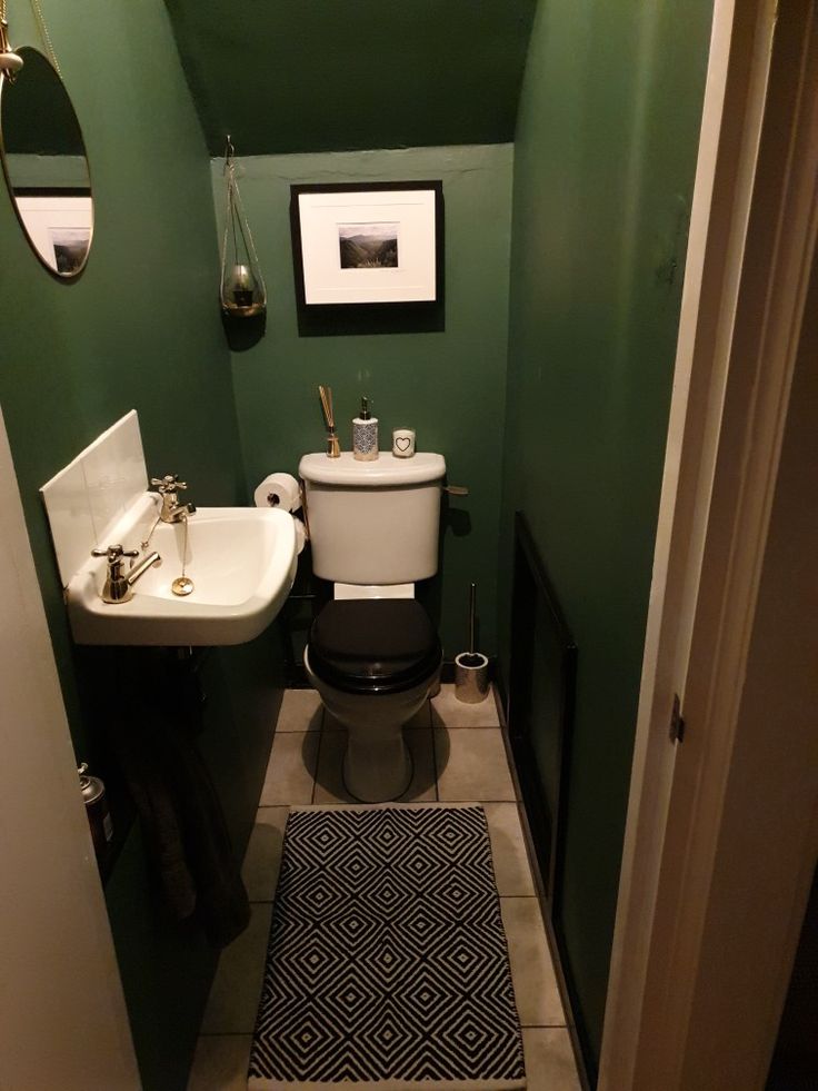 a small bathroom with green walls and white fixtures on the wall, along with a black rug