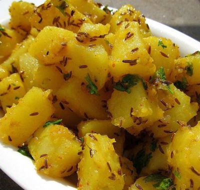 a white bowl filled with potatoes covered in herbs