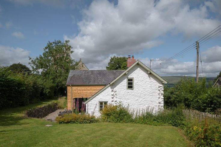 a white house sitting in the middle of a lush green field next to a forest