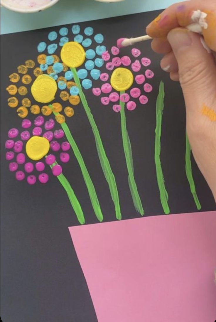 someone is painting flowers on a piece of paper