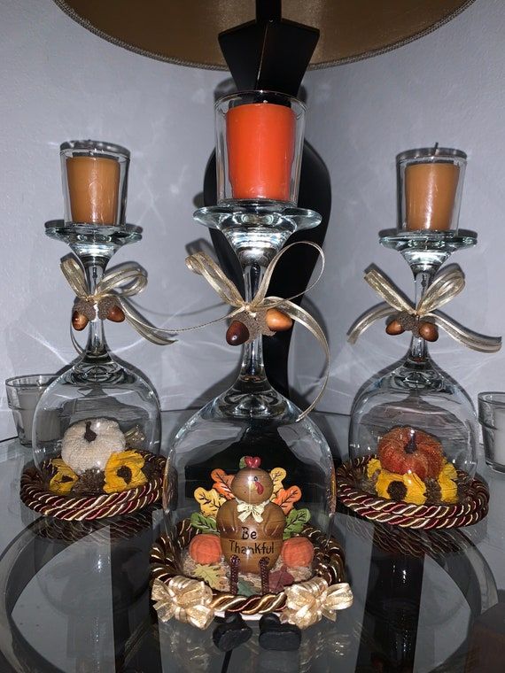 a glass table topped with three wine glasses filled with candles and candy cornucons