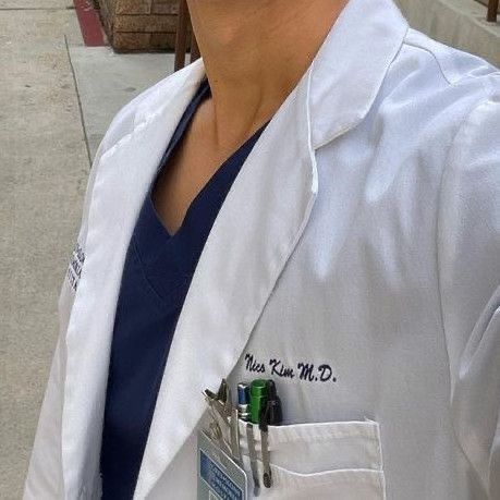 a woman wearing a white lab coat and holding a clipboard in her pocket while standing on the sidewalk