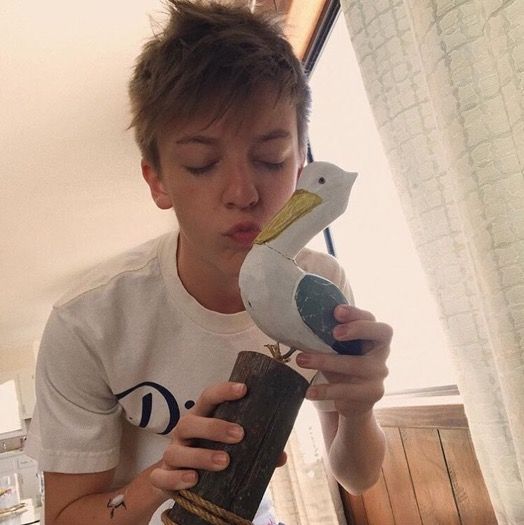 a young boy is holding a bird in his hand and looking at it's beak