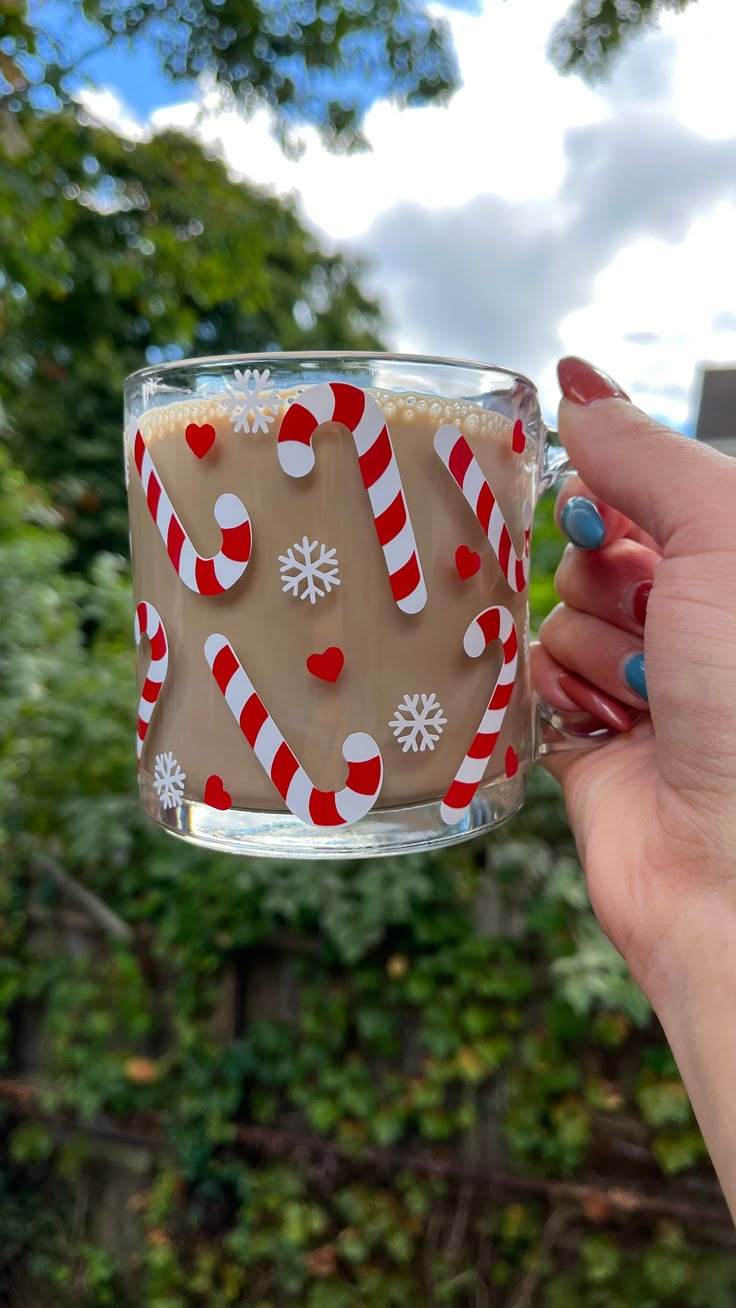 a person holding a cup with candy canes on it and frosting in the middle