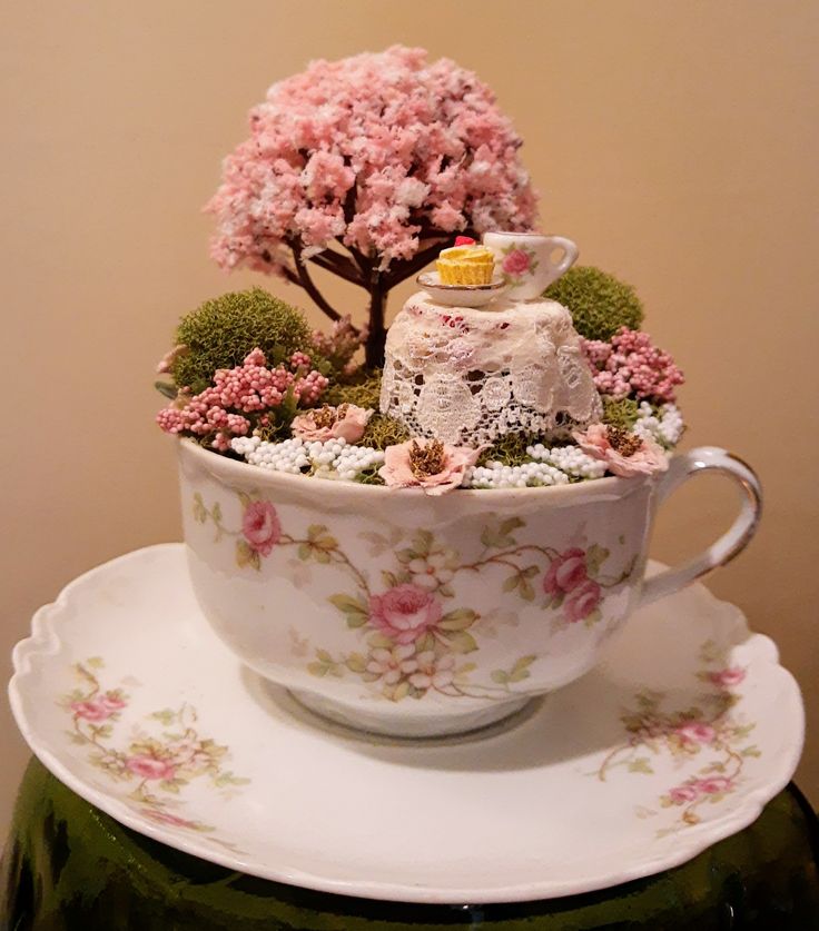 a teacup filled with flowers and plants on top of a table