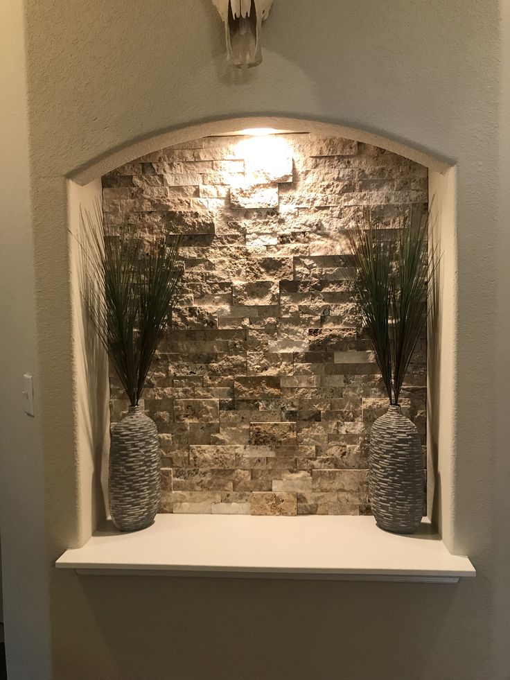 two vases with plants are sitting on a ledge in front of a stone wall