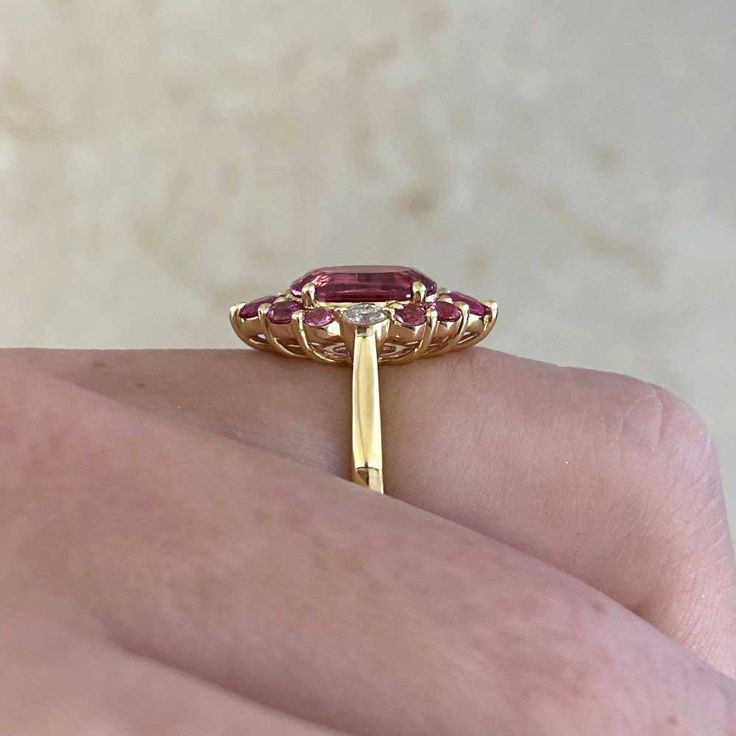 This gorgeous ring features a 1.92 carat oval-cut pink tourmaline ring that is set in prongs. Flanking either side of the stone are two oval-cut diamonds weighing approximately 0.11 carats. Additional prong-set rubies and spinel form a halo around the center stone. The total weight of the spinel is approximately 0.11 carats and the total weight of the rubies is approximately 0.25 carats. This ring is handcrafted in 18k yellow gold.
The measurements of the center tourmaline are 9.34mm x 6.53mm x Gia Certified Oval Pink Ruby Ring, Elegant Pink Emerald-cut Ruby Ring, Elegant Pink Emerald Cut Ruby Ring, Fine Jewelry Tourmaline Rings With Brilliant Cut, Luxury Pink Marquise Ring, Pink Marquise Ruby Ring For Formal Occasions, Formal Marquise Pink Ruby Ring, Formal Pink Marquise Ruby Ring, Pink Marquise Ruby Ring Fine Jewelry