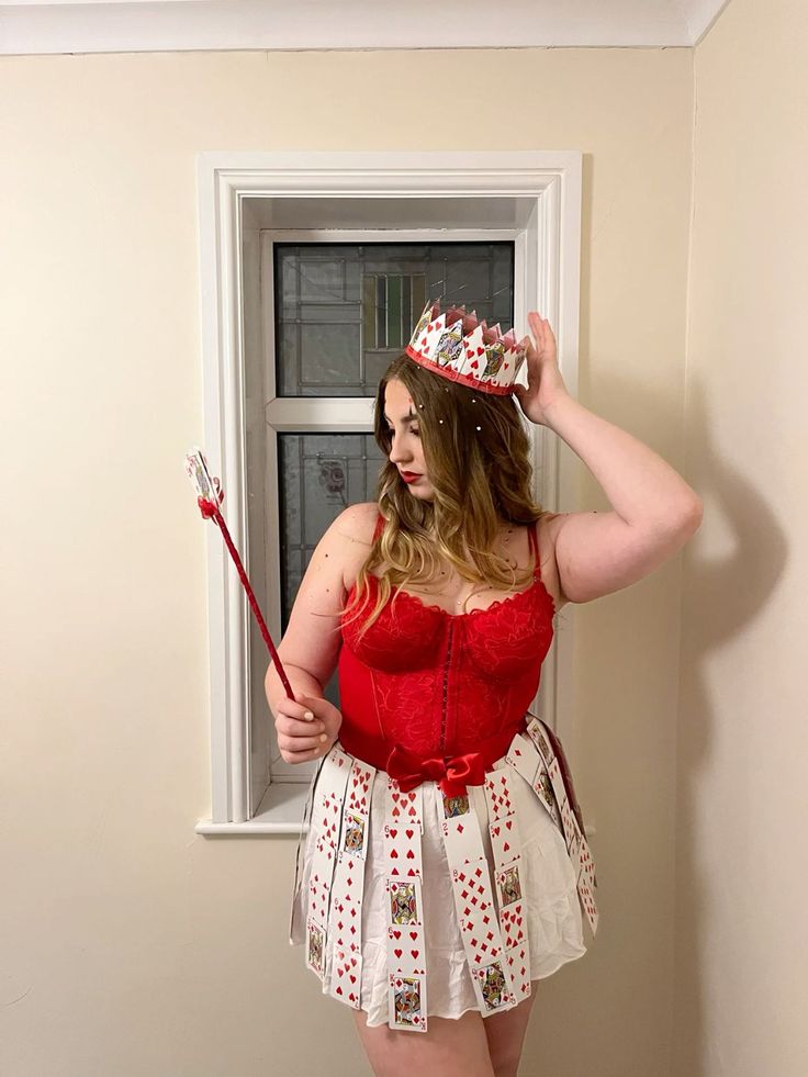 a woman in a red top and white skirt holding a broom while standing next to a window