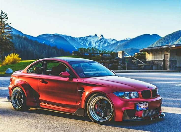 a red car parked in front of some mountains