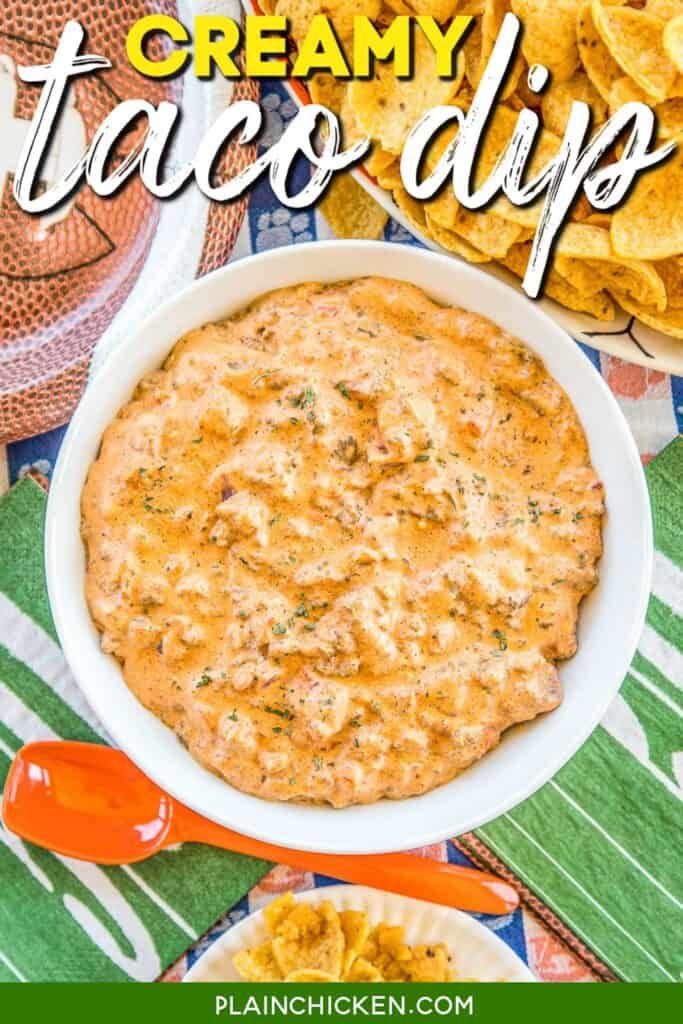 a white bowl filled with taco dip next to tortilla chips on a table