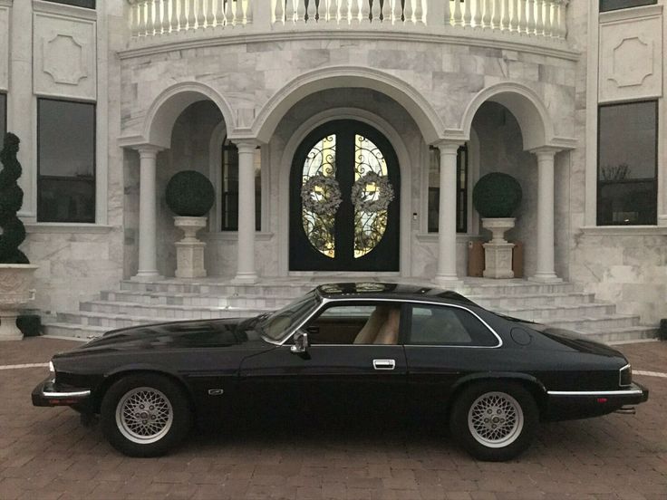 a black car is parked in front of a large white building with columns and arched windows