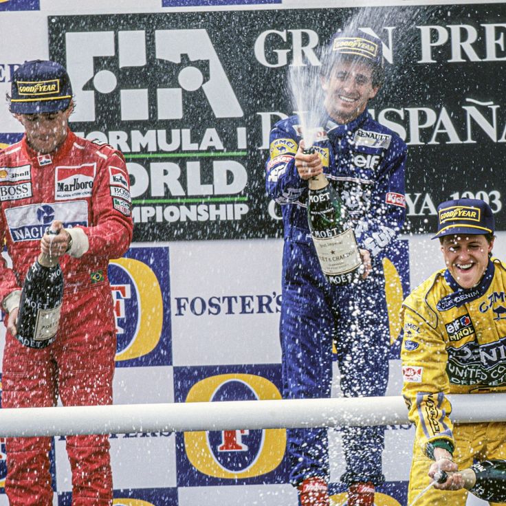 two men on the podium with champagne in their hands and one man holding up his fist