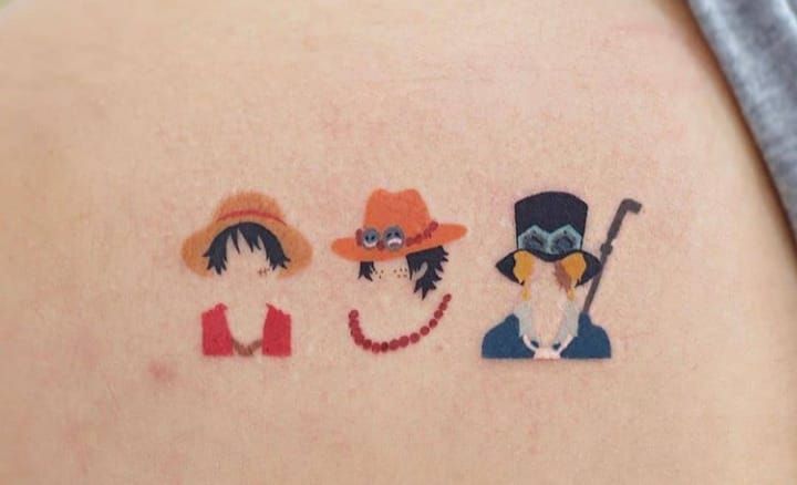 the back of a woman's shoulder with small tattoos on her left arm and two people wearing hats