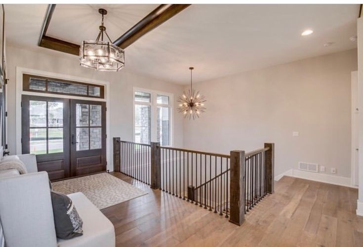 a living room filled with furniture and a chandelier hanging from the ceiling over a wooden floor