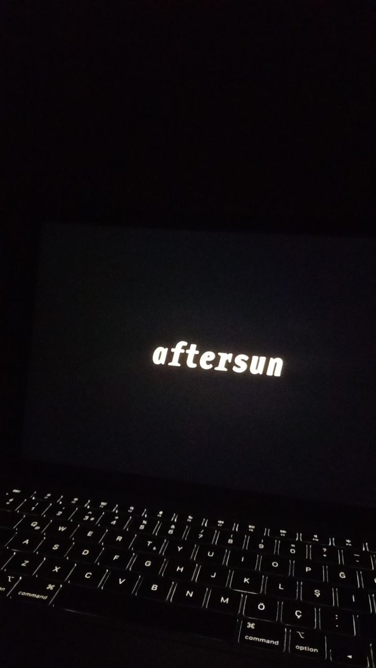 an open laptop computer sitting on top of a table in the dark with the word aftersun lit up