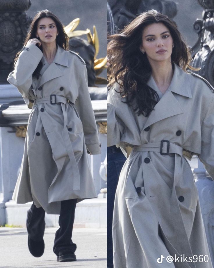 a woman in a trench coat walking down the street