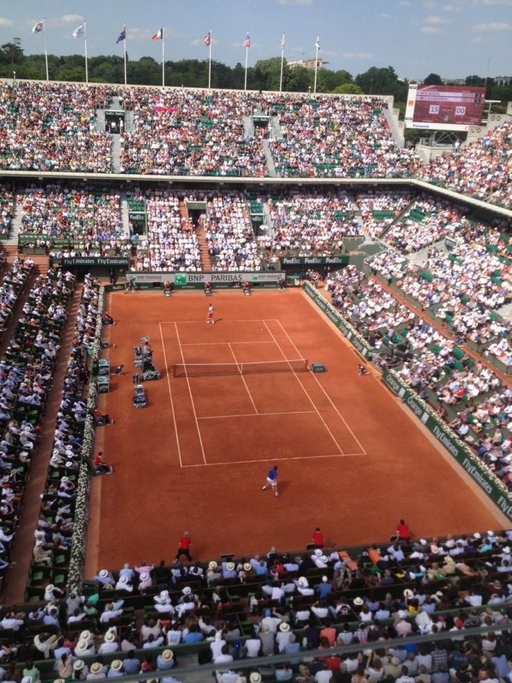 a tennis match is being played on a clay court with many people sitting in the stands