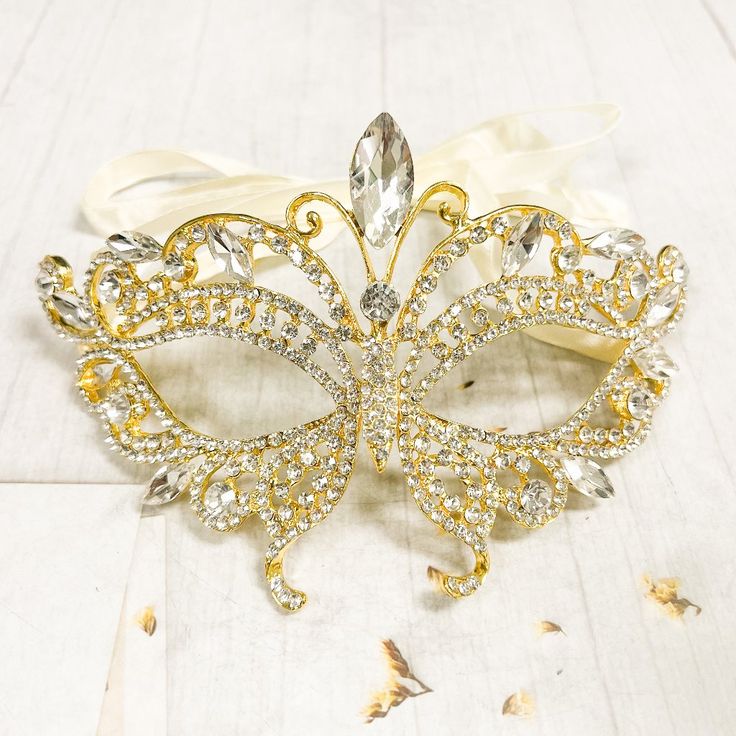 a masquerade mask with jewels and ribbons on a white tablecloth covered floor