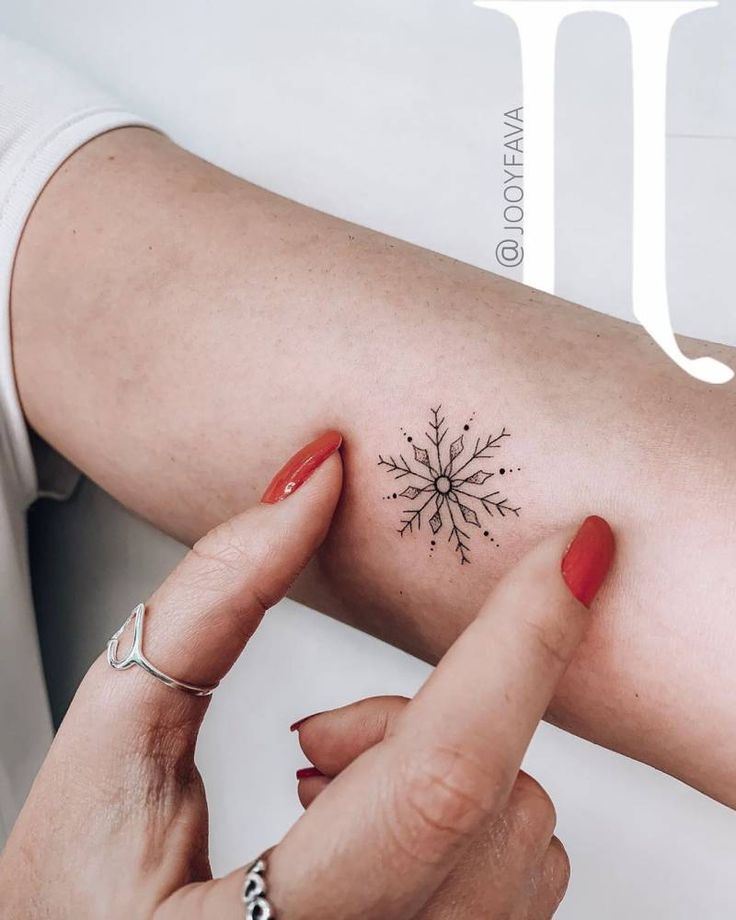 a woman's arm with a small snowflake tattoo on her left shoulder