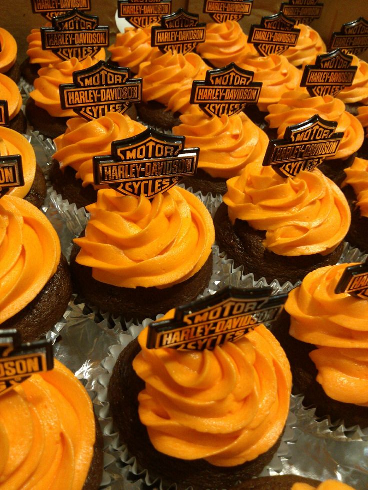 cupcakes with orange frosting and harley davidson stickers on them are displayed