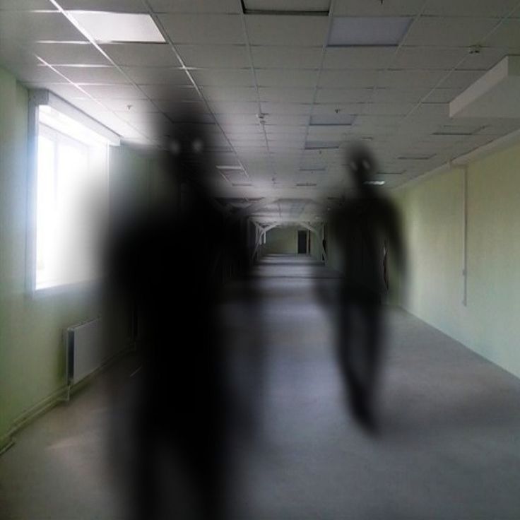 blurry photograph of two people walking down an empty hallway with no one in it