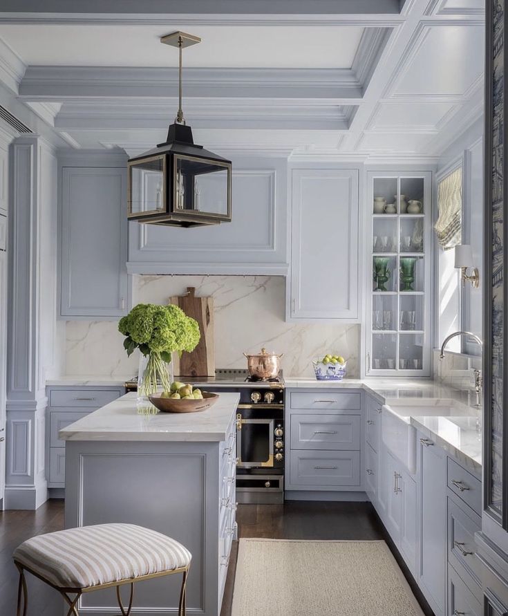 a kitchen with white cabinets and marble counter tops, along with an island in the middle