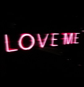 the word love me is lit up in the dark with red light on it's side