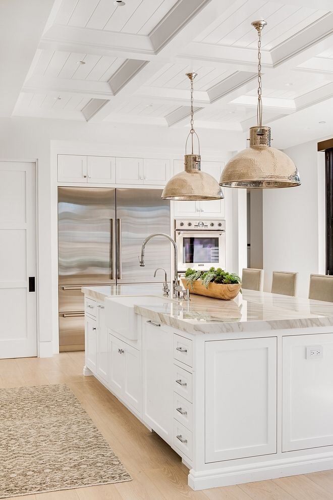 a large kitchen with white cabinets and an island in the middle is decorated with pink flowers