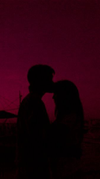 the silhouette of two people kissing in front of a pink sky at sunset or dawn