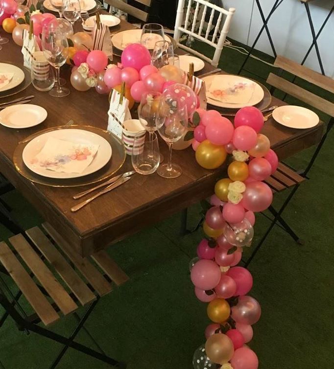 a table set with plates, glasses and balloons