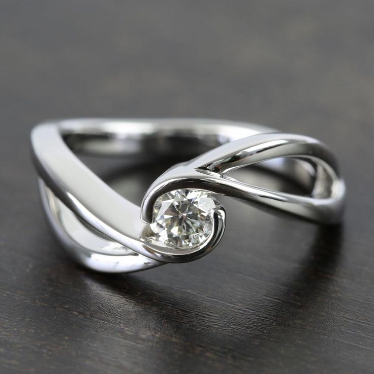 a white gold ring with a diamond in the center on a wooden table, close up